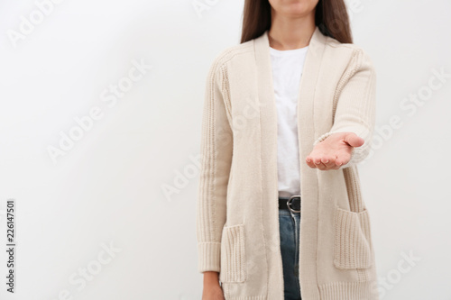 Woman giving helping hand on light background. Space for text