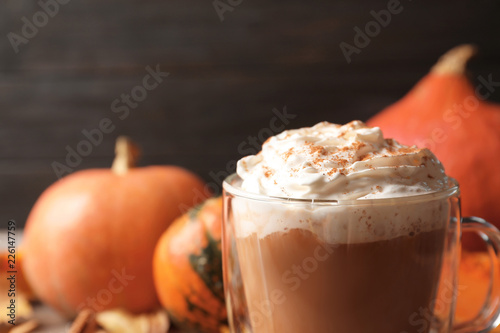 Glass cup with tasty pumpkin spice latte on table, closeup