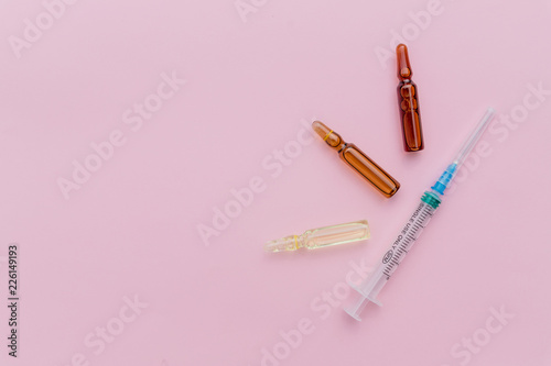Beauty Injection, facial skin lifting on pink background concept.Glass Medicine Vials ampule ,medicine pill and capsule isolated. concept of cosmetic injections.Copy space