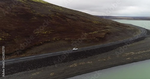 Aerial Shot of Car driving between a Mountain and a Lake photo