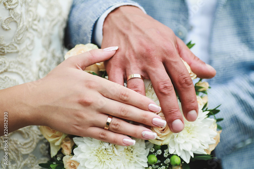hands of the newlyweds on the wedding bouquet