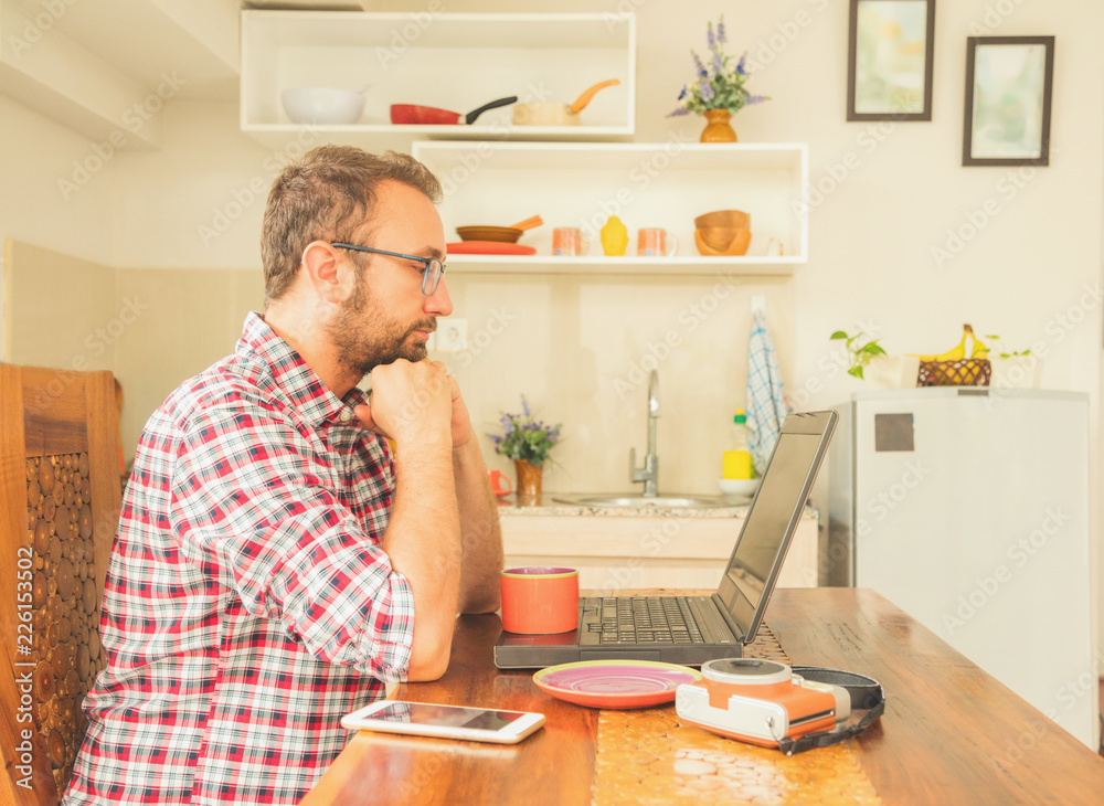 Modern bearded man using cellphone and drinking coffee with laptop. Modern bearded man using cellphone and drinking coffee with laptop.