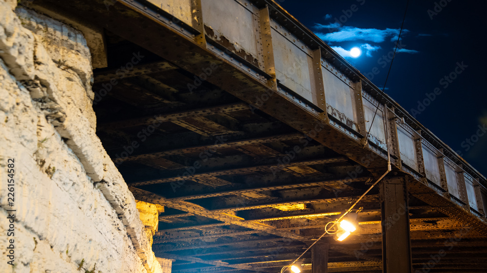 Urban city train bridge at night with a full moon