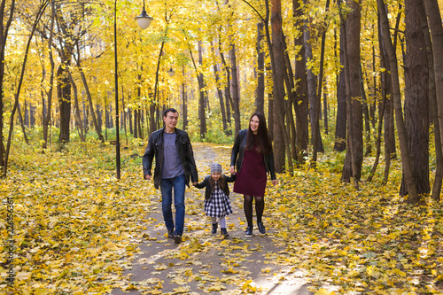 Fall, nature and family concept - happy family walking in autumn park