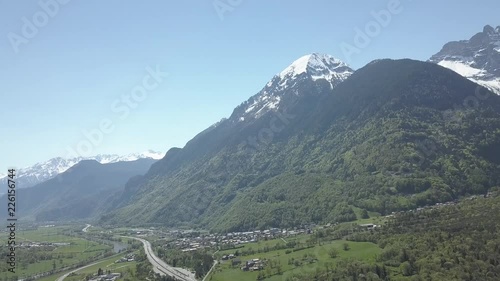 Aerial drone shot of a valley with roads and towns underneath snow covered mountains in Lavey Les Bains, Switzerland. photo