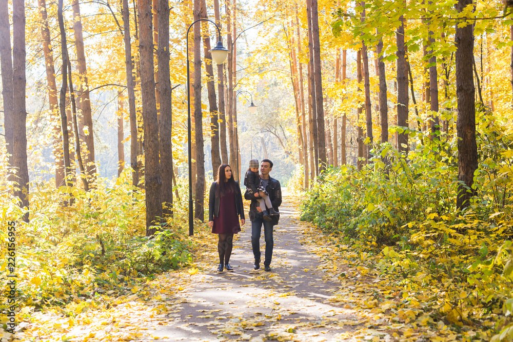 Parenthood, fall and people concept - young family happy in autumn park Parenthood, fall and people concept - young family happy in autumn park