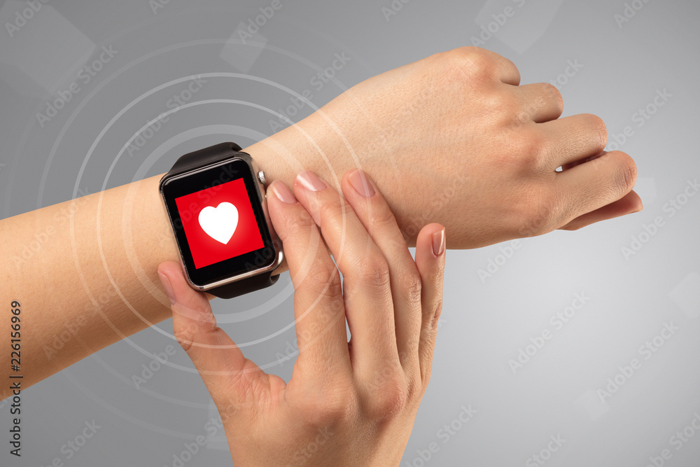 Fototapeta premium Naked female hand with smartwatch and with heart rate icon on the watch