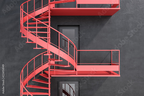 Gray building with red spiral fire escape stairs photo