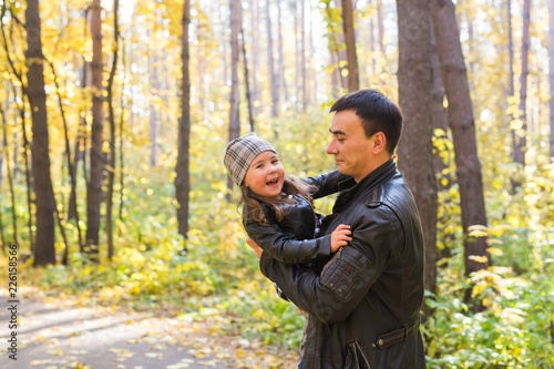 Fatherhood, children and family concept - Father holding his daughter in autumn park © satura_