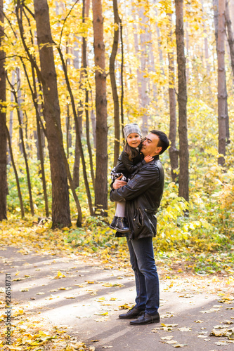 Family, autumn, people concept - father and daughter walking in autumn park. Daughter on dad's hands