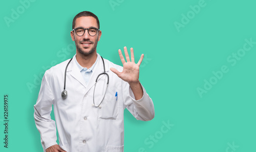 Confident young doctor with a gesture of number five