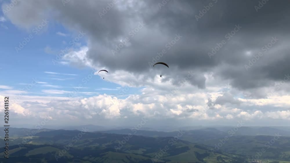 Two paragliders are flying in the sky above the mountains against the backdrop of amazing clouds. Two paragliders are flying in the sky above the mountains against the backdrop of amazing clouds.