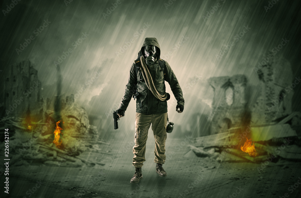 Fototapeta premium Destroyed place after a catastrophe with man in gas mask and weapon on his hand 