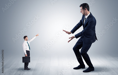 Small businessman in shirt pointing to an afraid businessman 