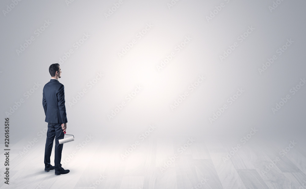 Man standing with his back in an empty room with object in his hand Man standing with his back in an empty room with object in his hand