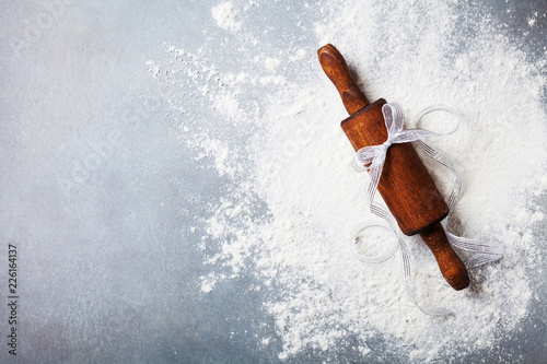 Bakery background for cooking christmas baking with rolling pin and scattered flour on kitchen table top view.
