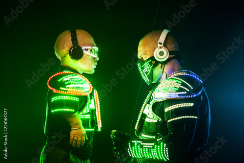 Εκτύπωση καμβά Mysterious man and midget in black wear, neon mask and gloves