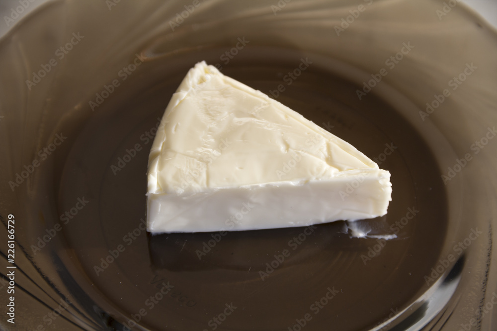 A piece of processed cheese is on a glass plate
