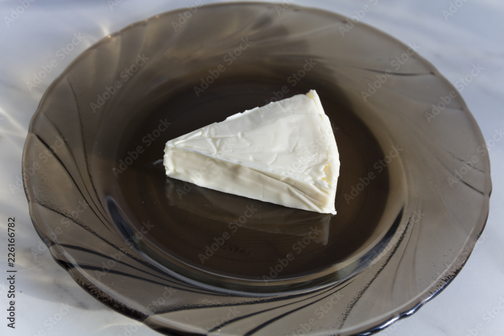 A piece of processed cheese is on a glass plate