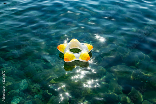 Little boy with life ring, swimming ring on the transparent water on the center of the picture