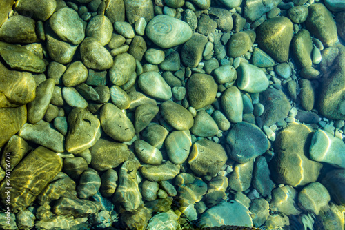 Pebbles in stream, transparent water as abstract background