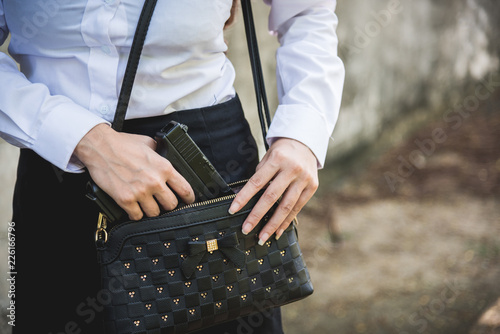 Woman hand holding removing small handgun from her purse