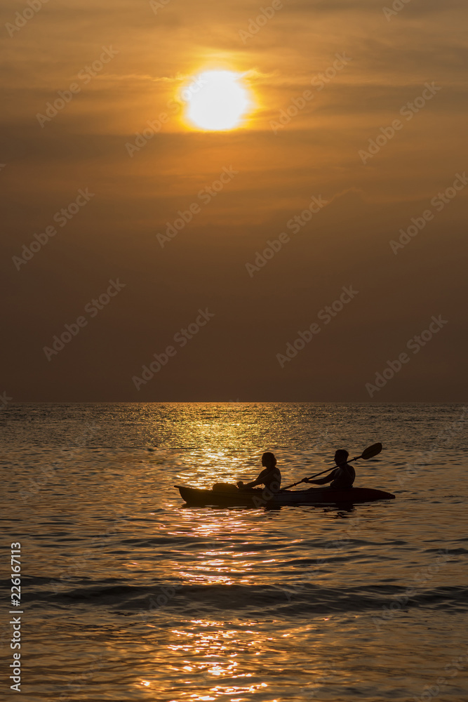 A man and a woman ride the boat in the rays of the setting sun