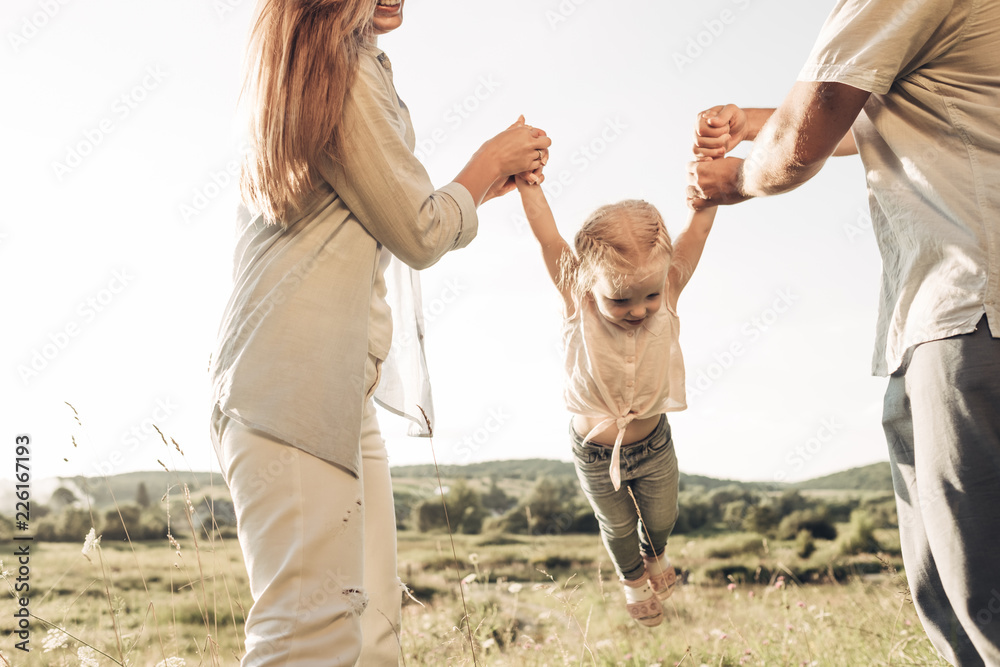 Young Adult Couple with Their Little Daughter Having Fun in the Park Outside the City, Family Weekend Picnic Concept, Three People Enjoying Summer Time