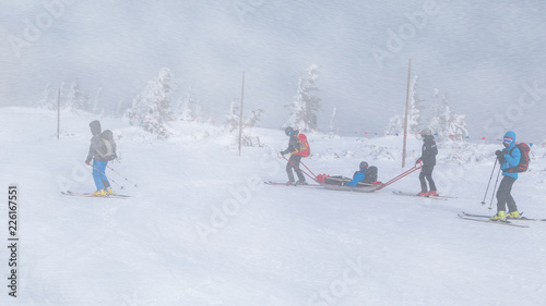 Ski rescue team with slide stretcher, brings help to ski during bad weather conditions.