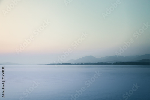 A beautiful, calm morning landscape of lake and mountains in the distance. Colorful summer scenery with mountain lake in dawn. Tatra mountains in Slovakia, Europe. © dachux21