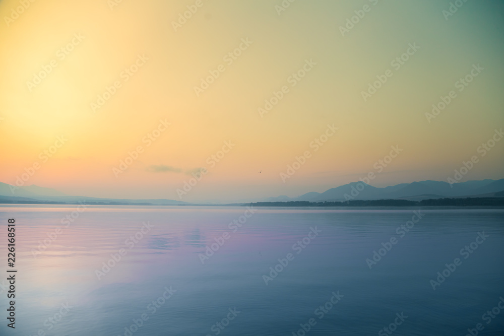 A beautiful, calm morning landscape of lake and mountains in the distance. Colorful summer scenery with mountain lake in dawn. Tatra mountains in Slovakia, Europe.