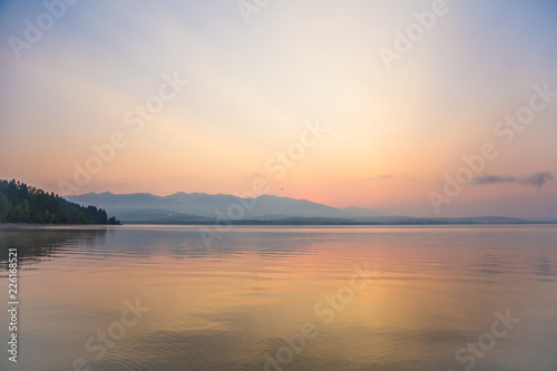 A beautiful  calm morning landscape of lake and mountains in the distance. Colorful summer scenery with mountain lake in dawn. Tatra mountains in Slovakia  Europe.