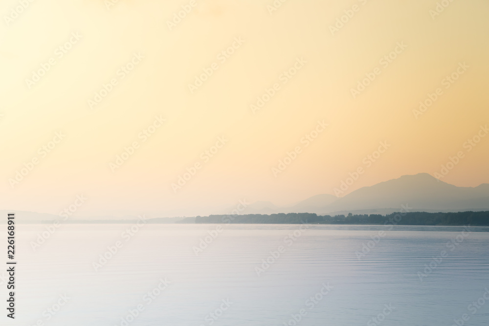 Naklejka premium A beautiful, calm morning landscape of lake and mountains in the distance. Colorful summer scenery with mountain lake in dawn. Tatra mountains in Slovakia, Europe.