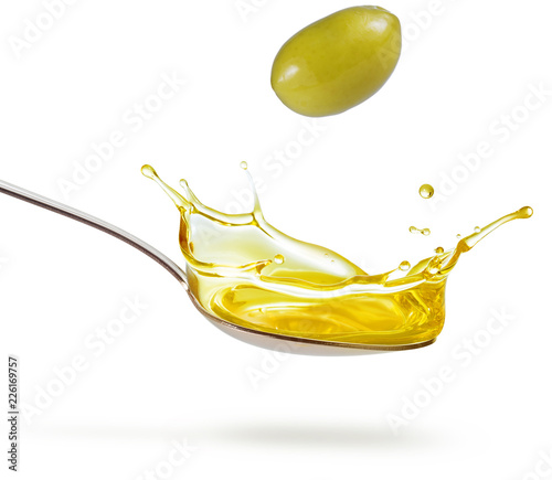 green olive falling on a splashing spoon of oil isolated on white