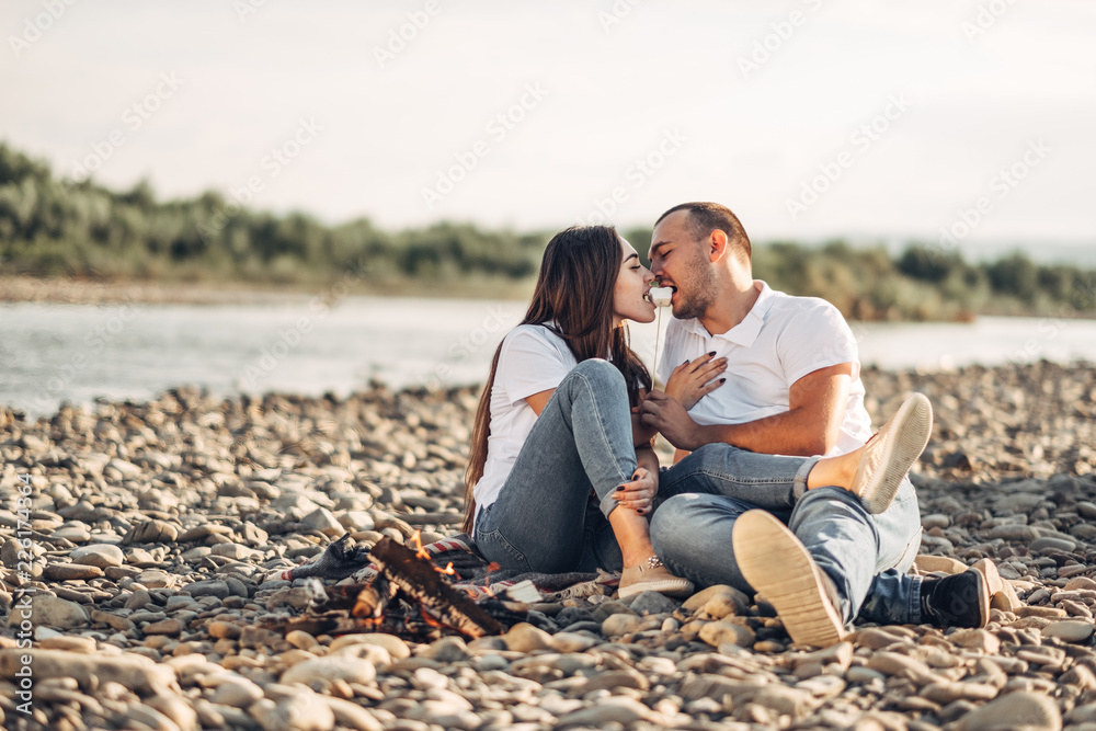 Fototapeta premium Happy Traveler Couple on Picnic into the Sunset with SUV Car