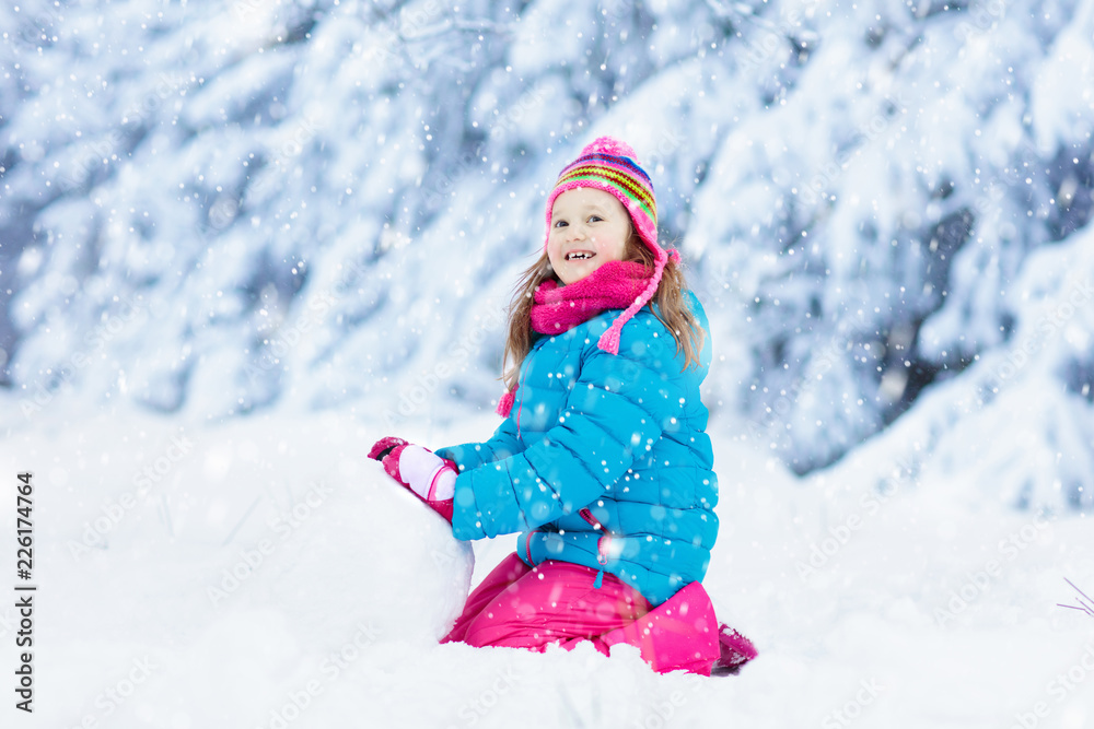 Child making snowman. Kids play in snow in winter Child making snowman. Kids play in snow in winter