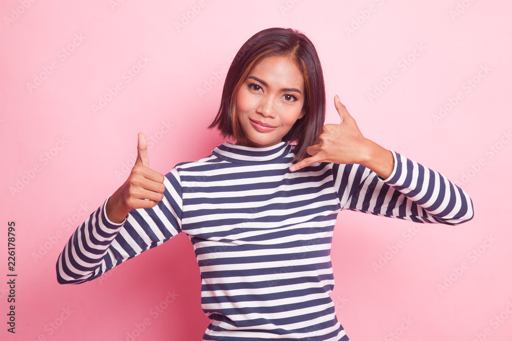 Young Asian woman thumbs up show with phone gesture.