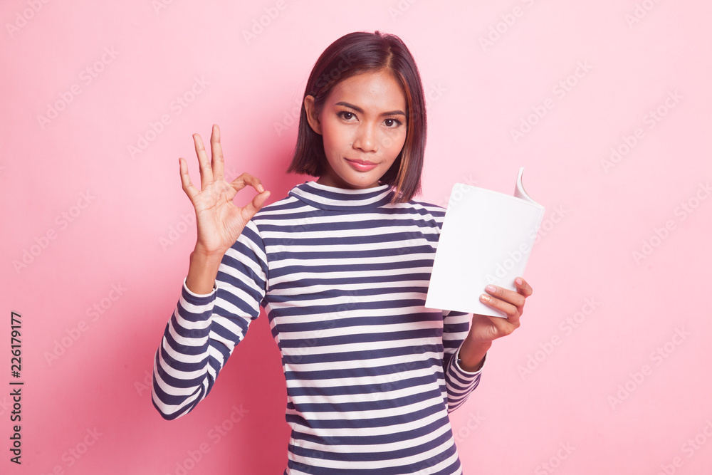 Young Asian woman show OK with a book. Young Asian woman show OK with a book.