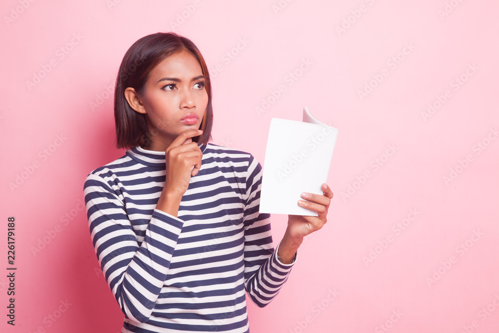 Young Asian woman with a book is thinking. Young Asian woman with a book is thinking.