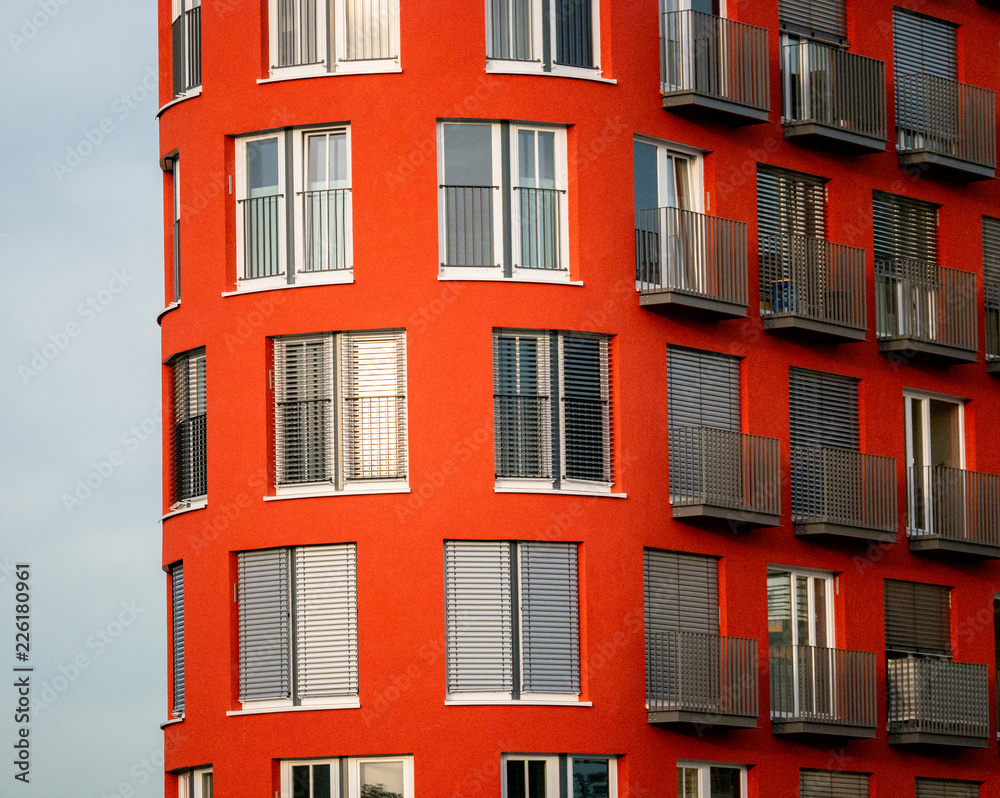 Image of red high rise building with windows and balconies and blinds ...