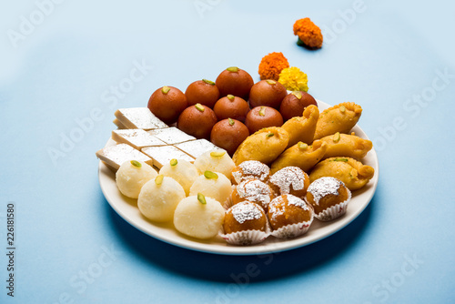 Indian sweets in a plate includes Gulab Jamun, Rasgulla, kaju katli, morichoor / Bundi Laddu, Gujiya or Karanji for diwali celebration photo