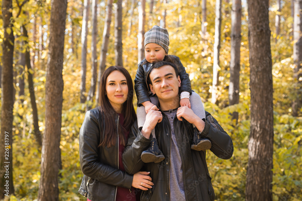 People, family and leisure concept - mother, father and little daughter have fun in autumn park