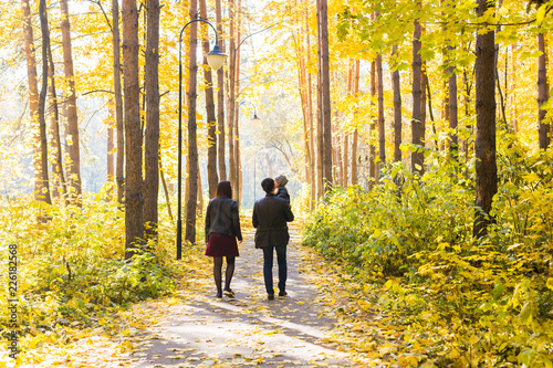 Fall, nature and family concept - family walking in autumn park, back view © satura_