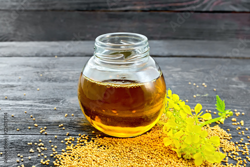 Oil mustard in jar with flower on board photo