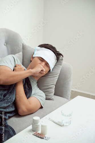 Man feeling bad lying in the couch and coughing