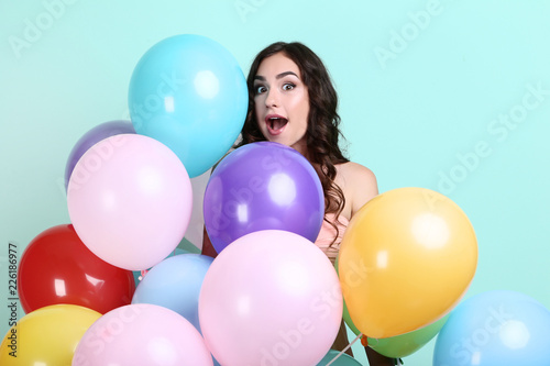 Young girl with colored balloons on mint background