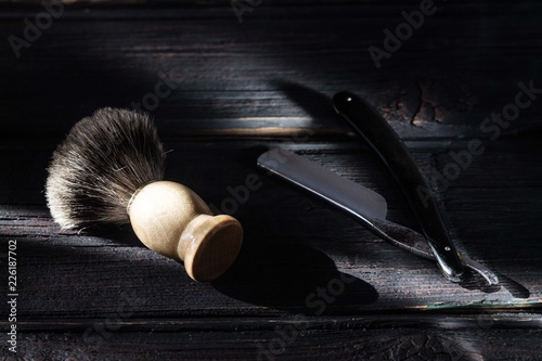 Straight razor and shaving brush on a luxury wooden background