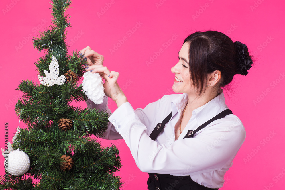 Christmas and holiday concept - Portrait of smiling young woman with Christmas tree over pink background Christmas and holiday concept - Portrait of smiling young woman with Christmas tree over pink background