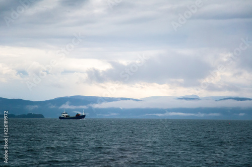 A dramatic  overcast scenery on the coeast of fjord during a ferry ride in Norway near Bergen. Moody autumn landscape of fjord.