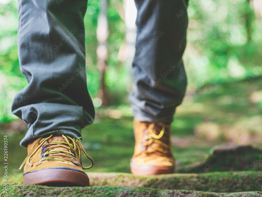 Fototapeta premium Hiking man with trekking boots on the bright green moss passage trail in forest